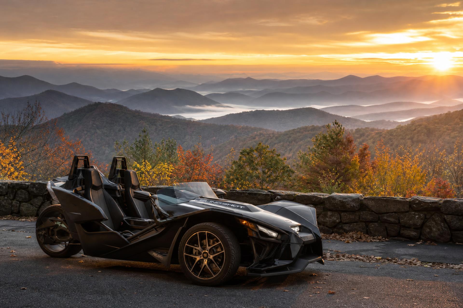A Polaris Slingshot parked at a Blue Ridge Parkway stone overlook at sunrise